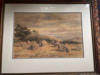 Full view of the framed watercolour painting showing hay stacks, large trees, and water body in the distance.