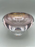Front and side angled view of round amber-tinted lead crystal votive holder with thick clear base.