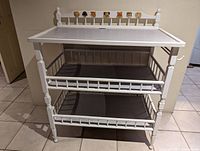 Front view of white infant change table with animal decals on top back rail and two lower shelves.