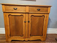 Front view of pine cabinet showing two drawers and two paneled doors with metal hardware.