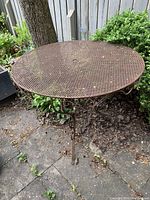 Photo of round ornamental metal garden table showing mesh top and weathering