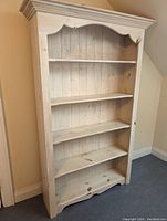 Front angled view of the large white pine bookshelf showing five shelves and decorative moulding.