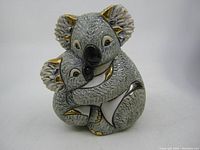 Front view of the koala and baby hugging figurine showing detailed fur texture and gold accents on ears and limbs.