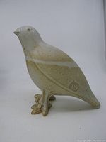 Side view of ceramic bird figurine showing signature on side and felt on tail end.