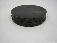 Closed black painted metal fly fishing tin showing overall shape and paint wear.