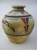 Front view of the pottery vase showing hand painted abstract fish and geometric designs in red, black and beige colors.