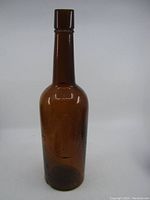 Full view of amber glass whisky bottle with tall neck, showing overall shape and color.