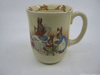 Front and side view of the Bunnykins mug showing the family breakfast bunny illustration and handle.