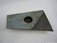 Top angled view of a rectangular ceramic flower tile with a circular metal pin holder in the center, glazed blue-gray with a dark leaf-patterned corner