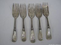 Top view of the five forks showing the mother of pearl handles and tarnished fork heads.
