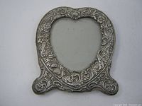 Front view of ornate heart-shaped sterling silver picture frame with floral and scroll design.