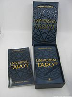 Closed box and instruction booklet for Universal Tarot Tarot set shown with dark blue geometric pentagram design and gold foil text.