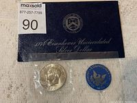 1974 Eisenhower silver dollar coin in original plastic pouch, certificate folder with US Treasury seal visible, and blue Eisenhower Uncirculated Silver seal.