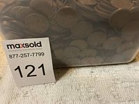 Plastic container filled with approximately 2000 mixed date wheat pennies, close-up showing coin edges and surfaces.