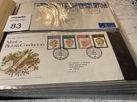 Photo of a black binder book with plastic protective sleeves containing British first day covers. Visible covers include themes of Music and British Conductors with various stamps and airmail labels.