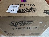 Photo of the top of the sealed cardboard case labeled 'Swiffer Wet Jet' containing four boxes of cleaning pads.