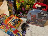 Photo showing the lot of new toys including Rescue Heroes action figures, Matchbox diecast car, Nerf accessory, and Spider-Man case with figure and vehicle.