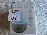 Front side of box showing PureSpa Drop USB Aroma Diffuser product with branding and features like all-natural aromatherapy, rainbow mood light, USB powered, and 5 year warranty.