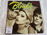 Front cover of the Blondie vinyl album showing three band members and the Blondie logo with some wear marks.