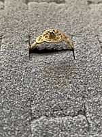 Front angle of ring showing central blue gemstone and filigree bezel