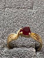 Angled front view showing red stone and twisted band design