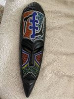 Full frontal view of the elongated wooden mask with detailed colorful beadwork on the face and forehead.