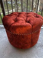 Full view of the round velvet ottoman footrest showing tufted top and velvet upholstery with rope detail.