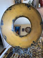 Round metal mirror with distressed yellow and black paint, donut shape with center mirror, shown from front view