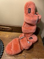 Pair of pink Ugg furry slide sandals displayed upright showing plush straps and footbed, black UGG logo tag visible.