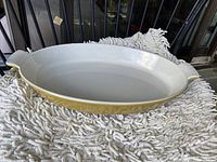 Photo of the oval cast iron enamelled casserole dish with exterior yellow and cream-white interior, showing the top side.