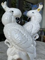 Side angle showing detailed feather texture and shape of both vintage ceramic cockatoo statues