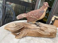 Side view of the wooden bird carving on natural wood base showing detailed carving and natural wood texture.