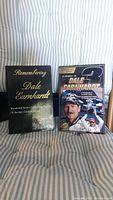 Two hardcover books showing covers: 'Remembering Dale Earnhardt' with black cover and gold text; 'Tribute to Dale Earnhardt' with photo of Dale Earnhardt and racing car number 3