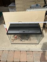 Top angled view of aquarium with black lid and measurement tape showing width.