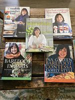 Front covers of five Barefoot Contessa cookbooks by Ina Garten arranged on a wooden table.