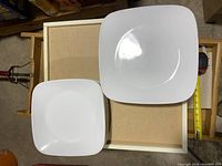 Top view showing one large and one medium white square Corelle plate for size comparison.