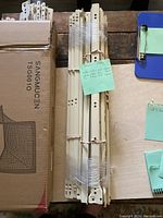 Drawer slides bundled showing taped pairs of white and tan metal slides with multiple mounting holes.