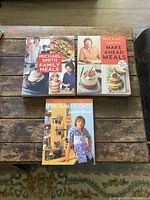 Top view of three cookbooks laid flat: 'Family Meals' and 'Make Ahead Meals' by Michael Smith, and 'The Naked Chef' by Jamie Oliver.