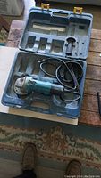 Makita angle grinder placed inside open Mastercraft case showing tool and case compartments.