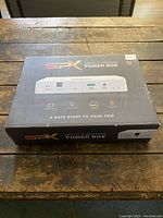 Front view of SPX Multifunction Power Box in box on wooden table.