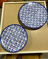 Two close-up views showing blue and white floral geometric pattern on two plates, highlighting design and condition.