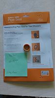 Front view of single Schluter Kerdi pipe seal in original packaging with installation instructions visible, orange and white packaging.