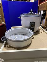Front view of Salton rice cooker with its steaming basket placed in front.