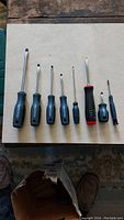 Seven screwdrivers laid out with flathead tips and different handle sizes and colors