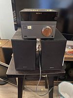 Front view of Sony CD player on top of two speakers on a table, showing logo and control dial.