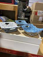 Three square ceramic serving bowls with handles, each featuring different blue and white patterns, placed on a counter.