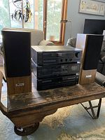 Wide view of Sony stereo components stacked with speakers on each side on wooden table