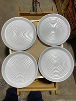 Four white rippled surface dinner plates displayed on a wooden tray showing the texture and size of the plates.