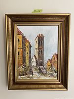 Framed painting of a vintage city street scene showing buildings, a tower, and a person walking. The painting is signed and measures 17x21 inches including frame.