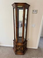Full view of the wooden curio cabinet with glass shelves and mirrored back inside.